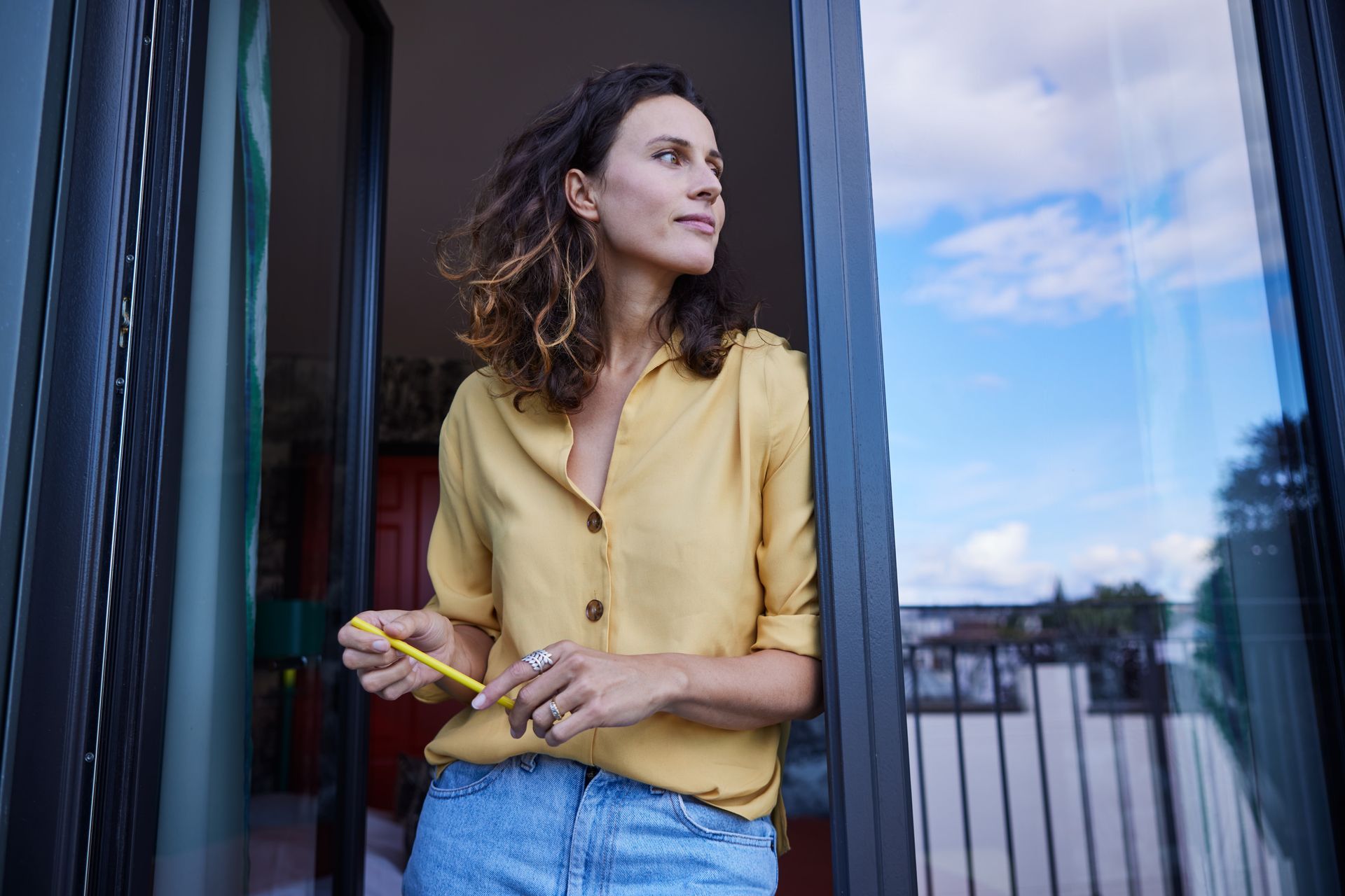 Eine Frau steht auf einem Balkon und schaut aus einem Fenster.