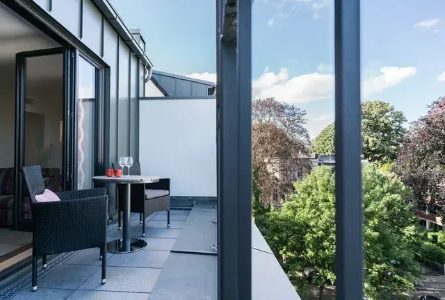 Ein Balkon mit Tisch und Stühlen und Blick auf Bäume