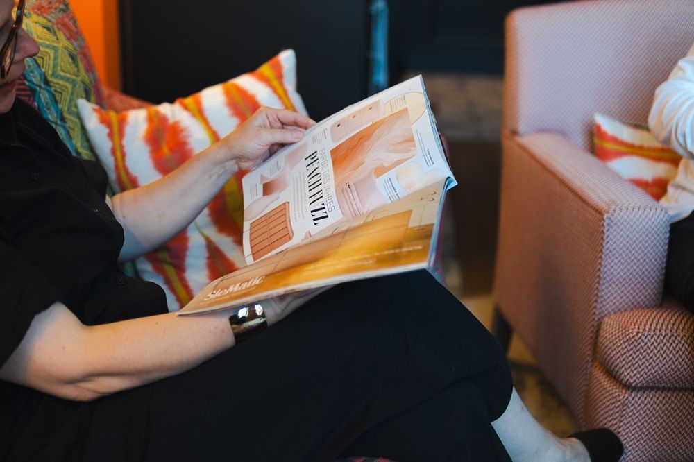 Eine Frau sitzt auf einem Sofa und liest eine Zeitschrift.