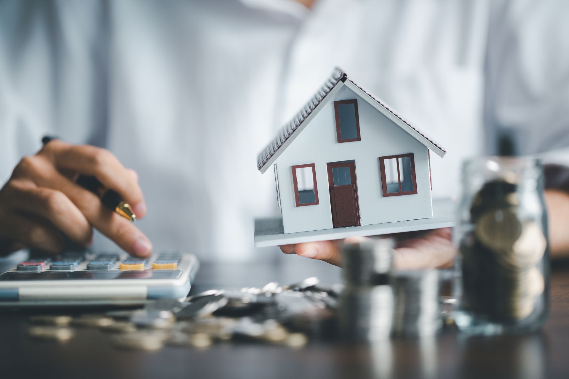 Un professionnel qui tient une maison et une calculatrice