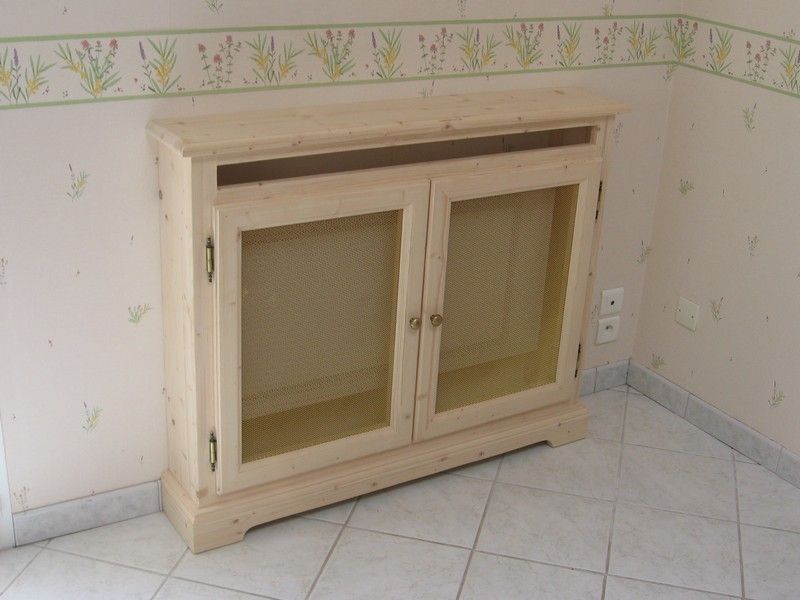 Un meuble en bois clair à portes vitrées, adossé à un mur tapissé de papier peint à motifs, sur un sol carrelé.