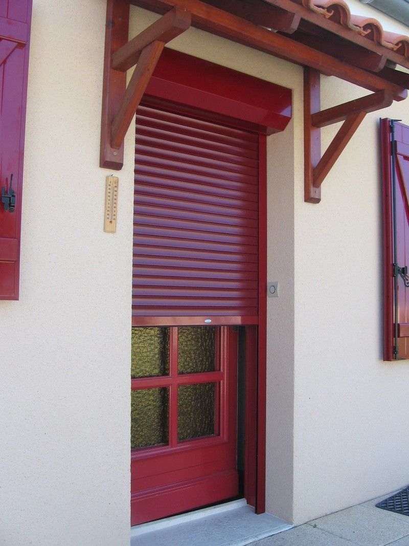 Un volet roulant rouge devant une porte