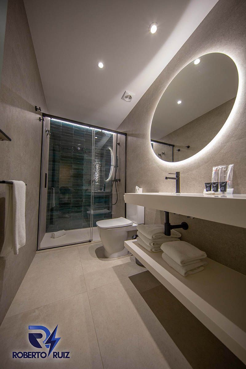 Un baño con inodoro, lavabo, espejo y ducha.