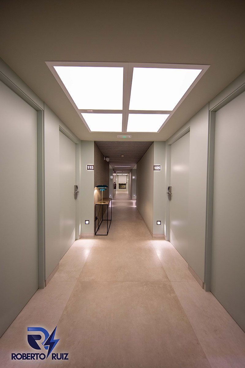 Un largo pasillo con puertas blancas y una luz en el techo.
