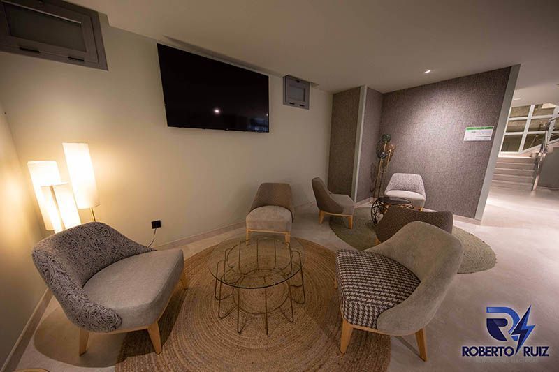 Una sala de estar con sillas, una mesa y un televisor de pantalla plana.