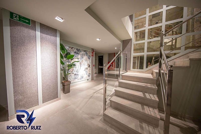 Un pasillo con escaleras y una señal de salida verde.