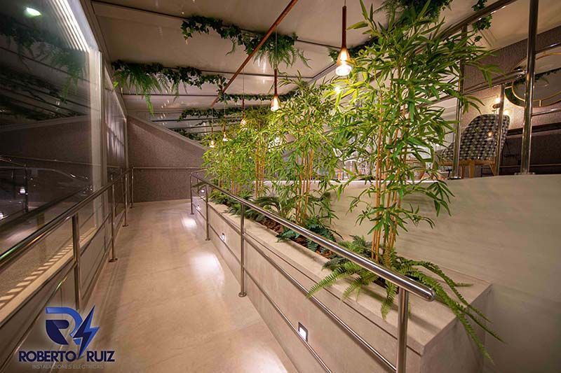 Un largo pasillo con plantas y una barandilla de acero inoxidable.