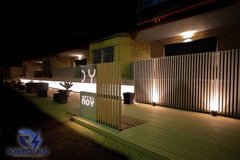 Un edificio con una valla de madera delante está iluminado por la noche.