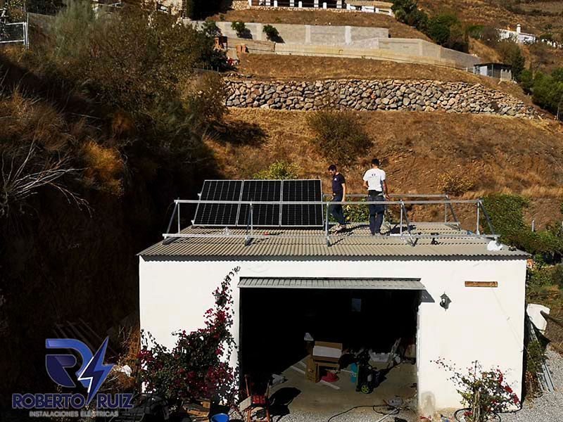 Un hombre está parado en el techo de un garaje con paneles solares.