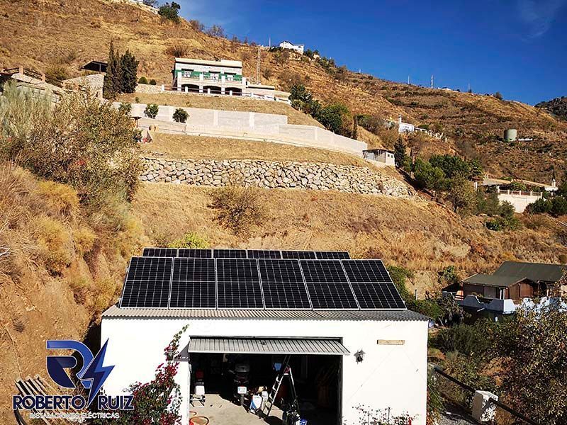 Un garaje con paneles solares en el techo está situado en la cima de una colina.