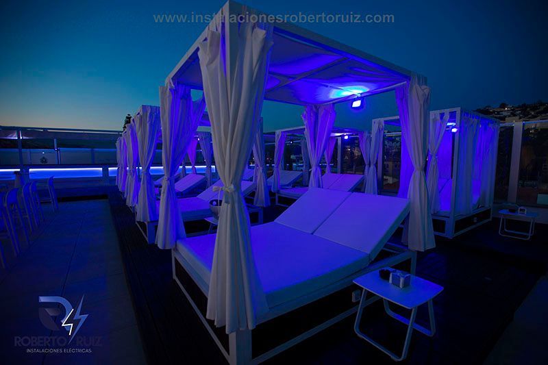 Una hilera de camas con dosel están iluminadas con luces azules.