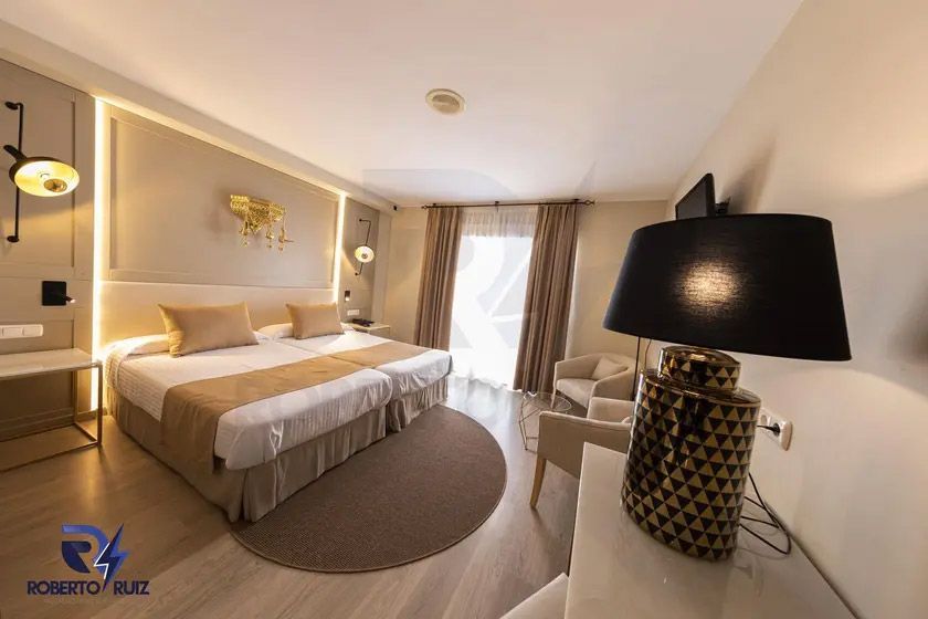 Una habitación de hotel con una cama, una silla, una lámpara y una televisión.