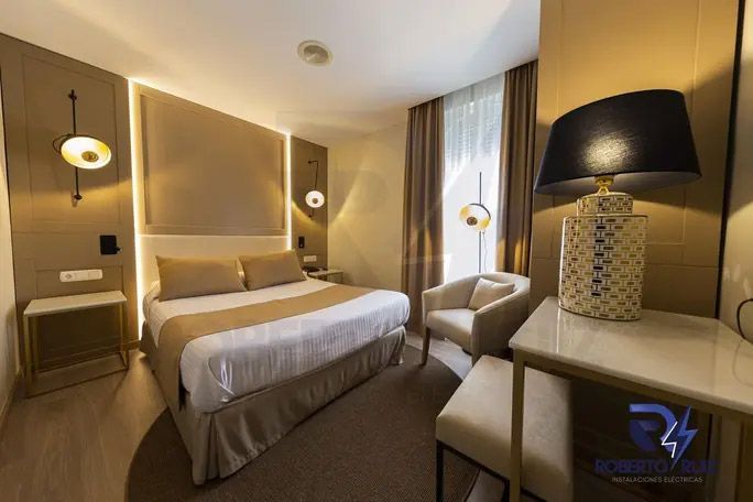 Una habitación de hotel con una cama, una silla, una mesa y una lámpara.