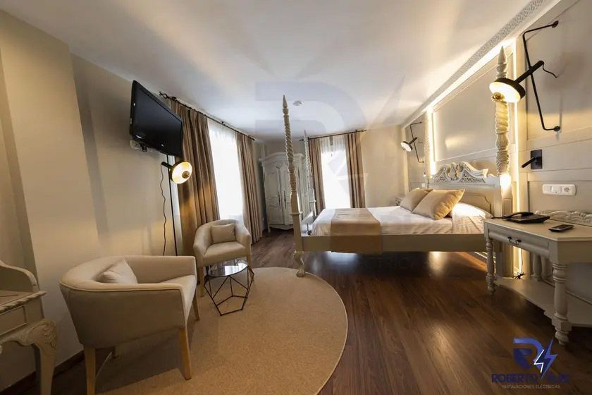 Una habitación de hotel con una cama, sillas, mesa y televisión.