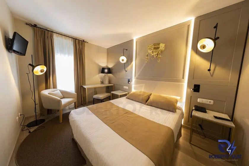 Una habitación de hotel con una cama, una silla, un escritorio y una televisión.