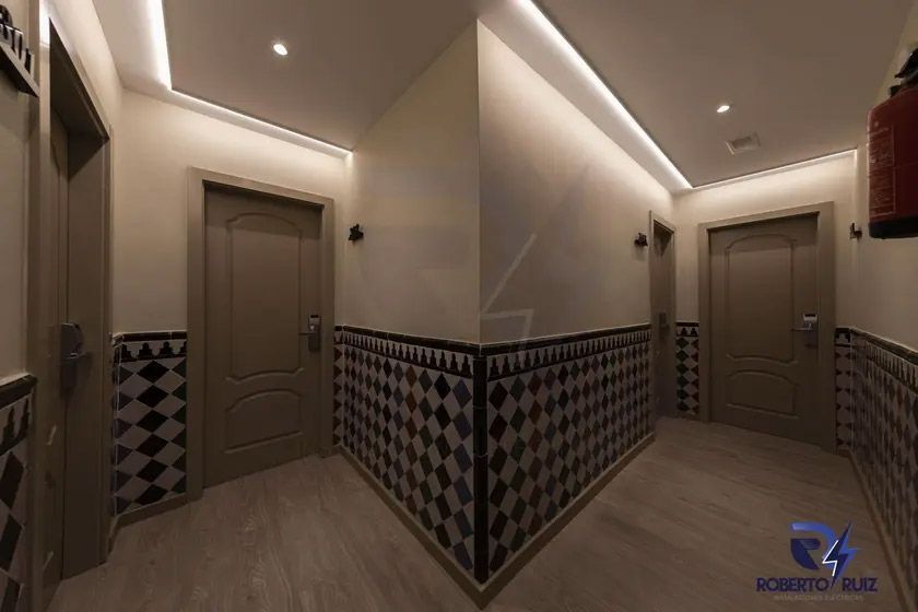 Un pasillo largo con muchas puertas y una pared de azulejos.