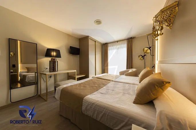 Una habitación de hotel con dos camas, un escritorio y un espejo.