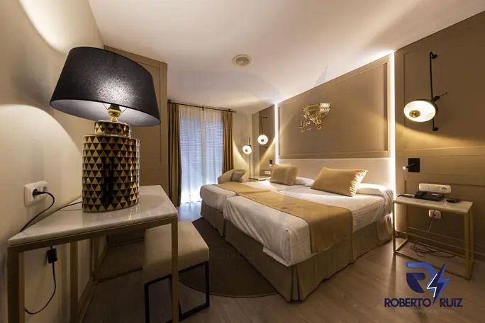 Una habitación de hotel con dos camas, una mesa y una lámpara.