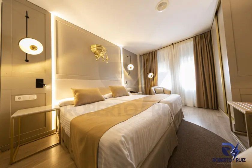 Una habitación de hotel con dos camas, una silla y una ventana.