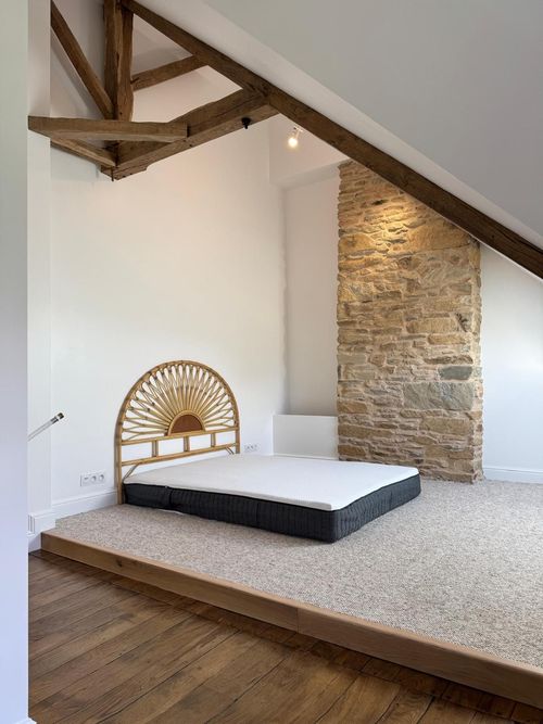Intérieur d'une maison en construction avec poutres de toit apparentes, cloisons sèches et murs non finis.