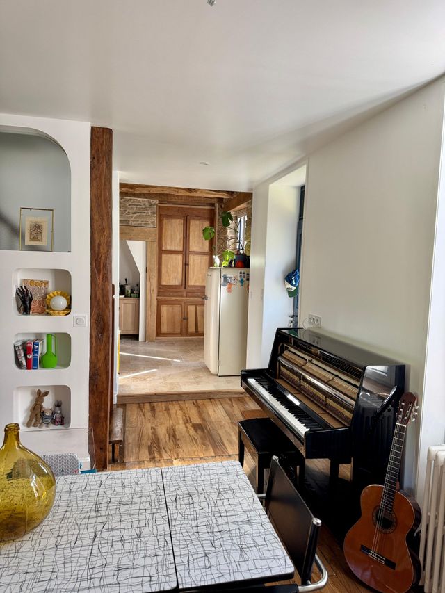 Pièce vide avec parquet, table pliante, chaises et matériaux de construction dans un intérieur partiellement rénové.