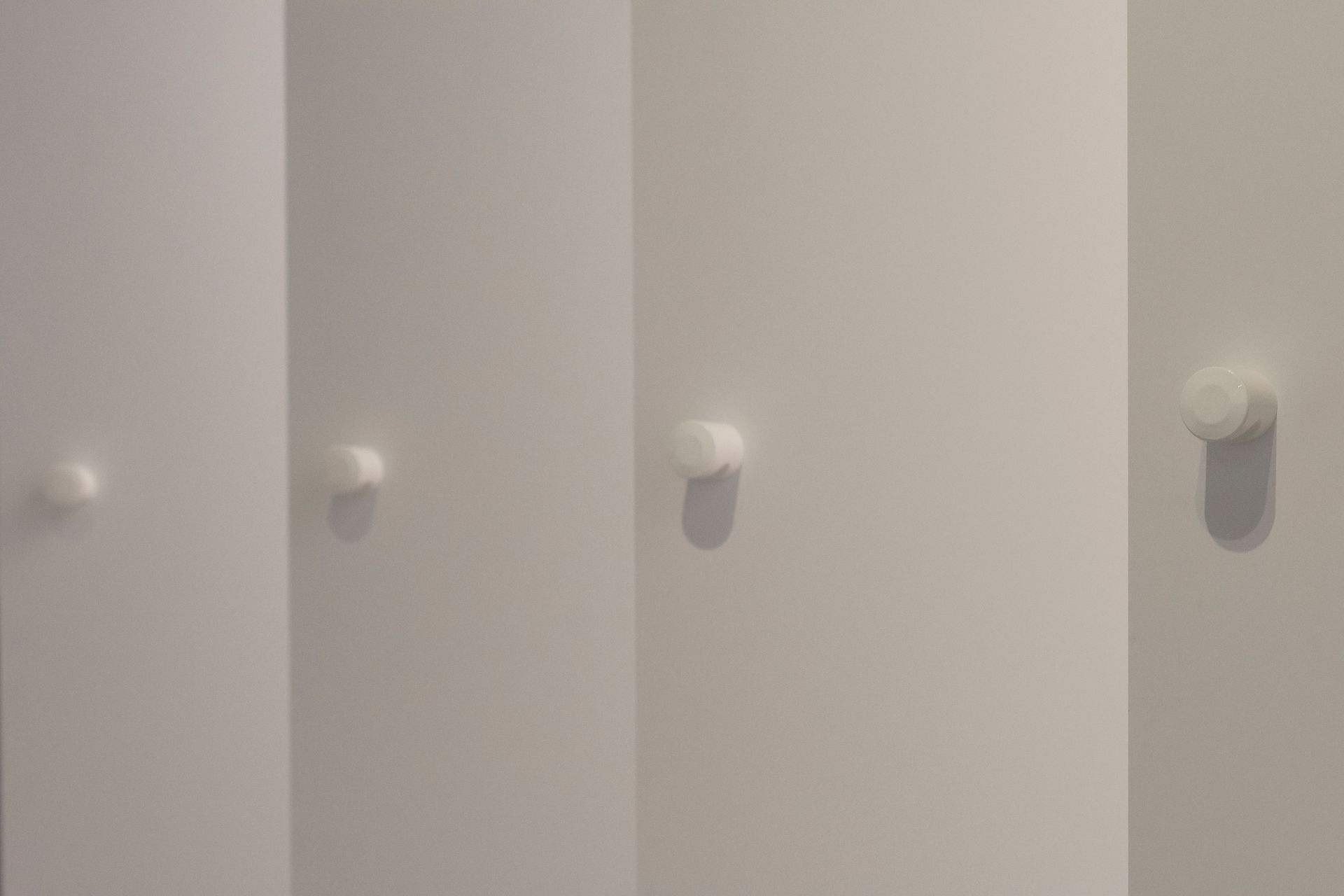 Quatre boutons blancs sur des portes de placard.