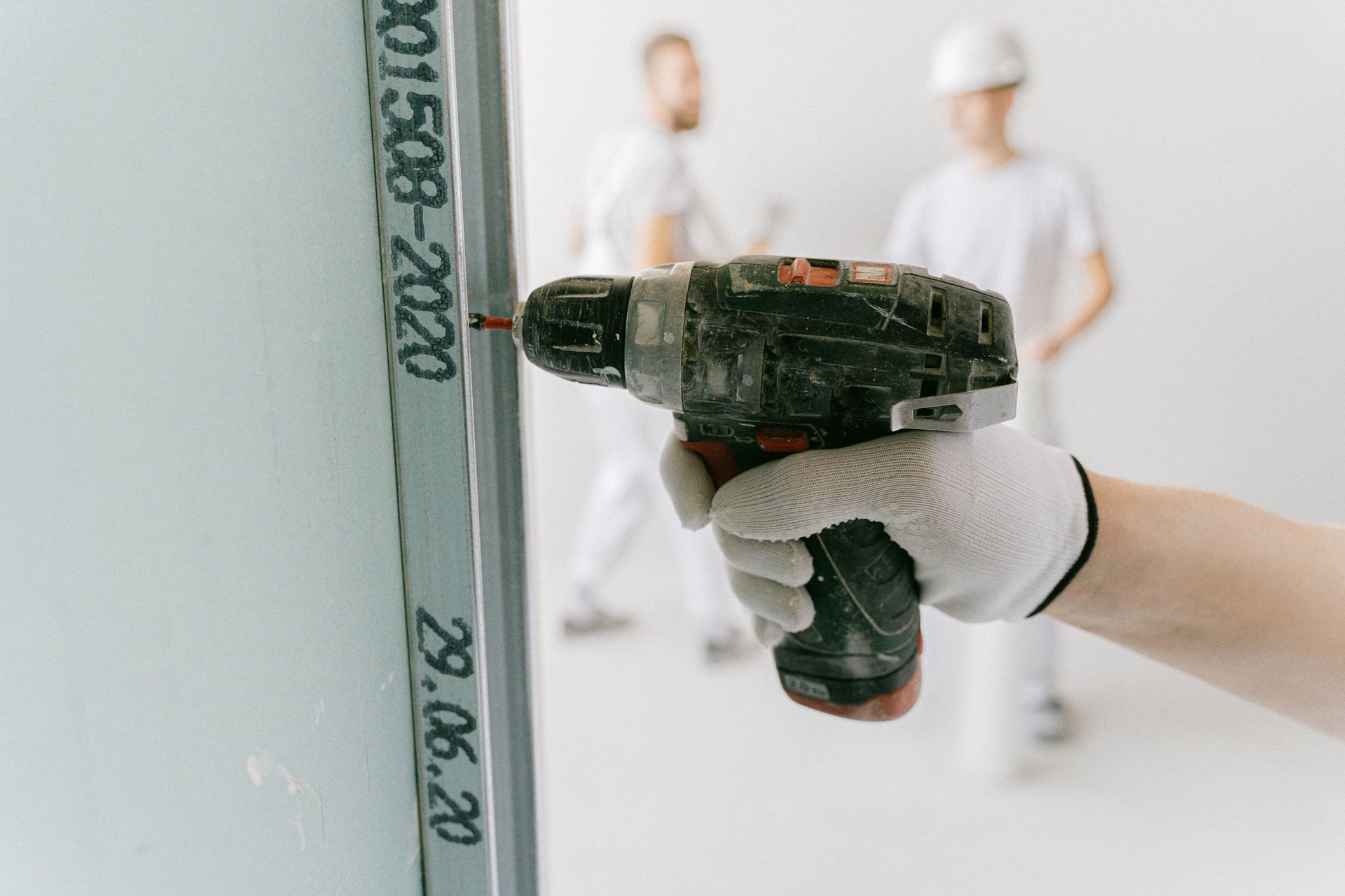 Main gantée utilisant une perceuse sur une structure métallique.