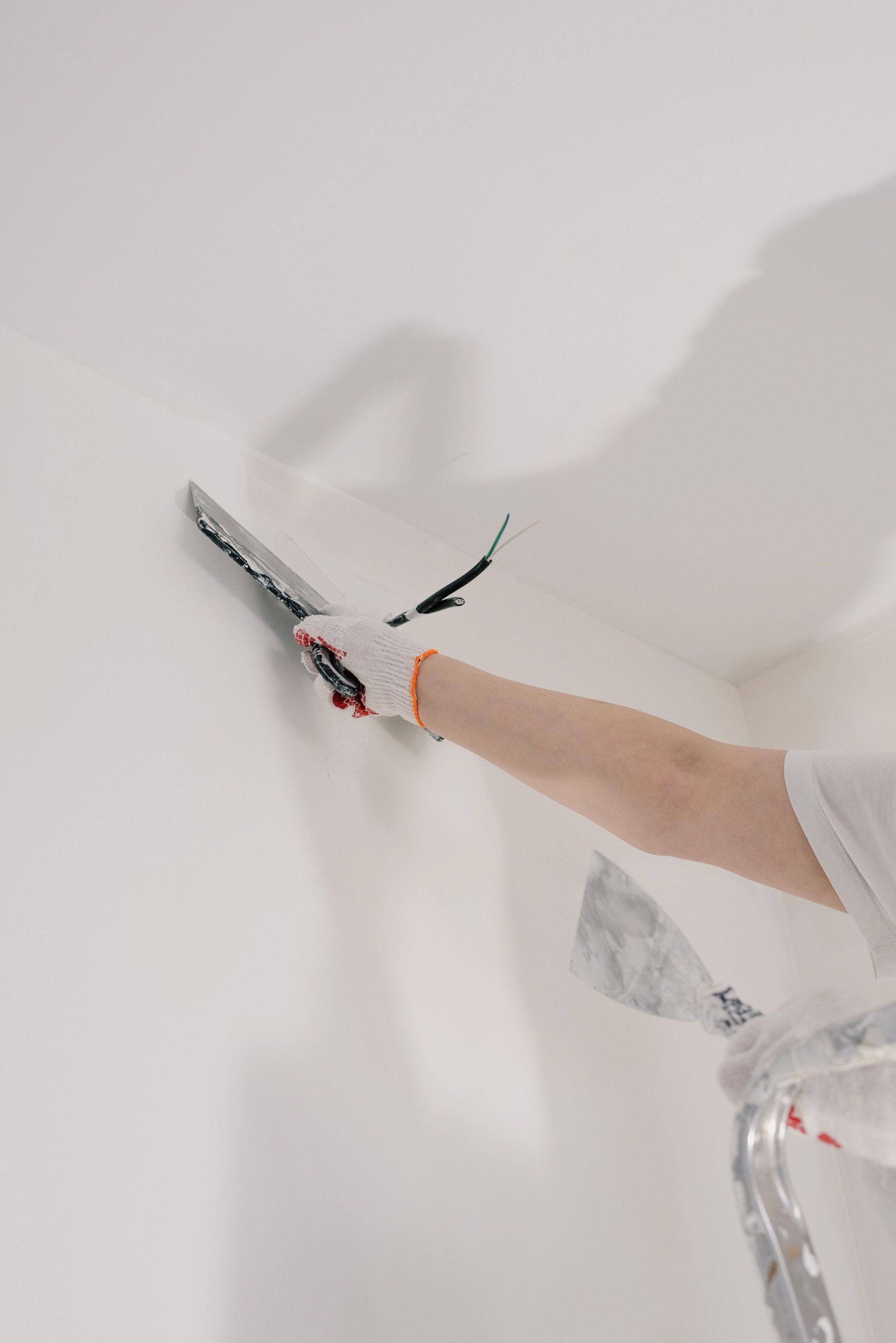 Application d’enduit mural avec une spatule lors de travaux de rénovation intérieure.