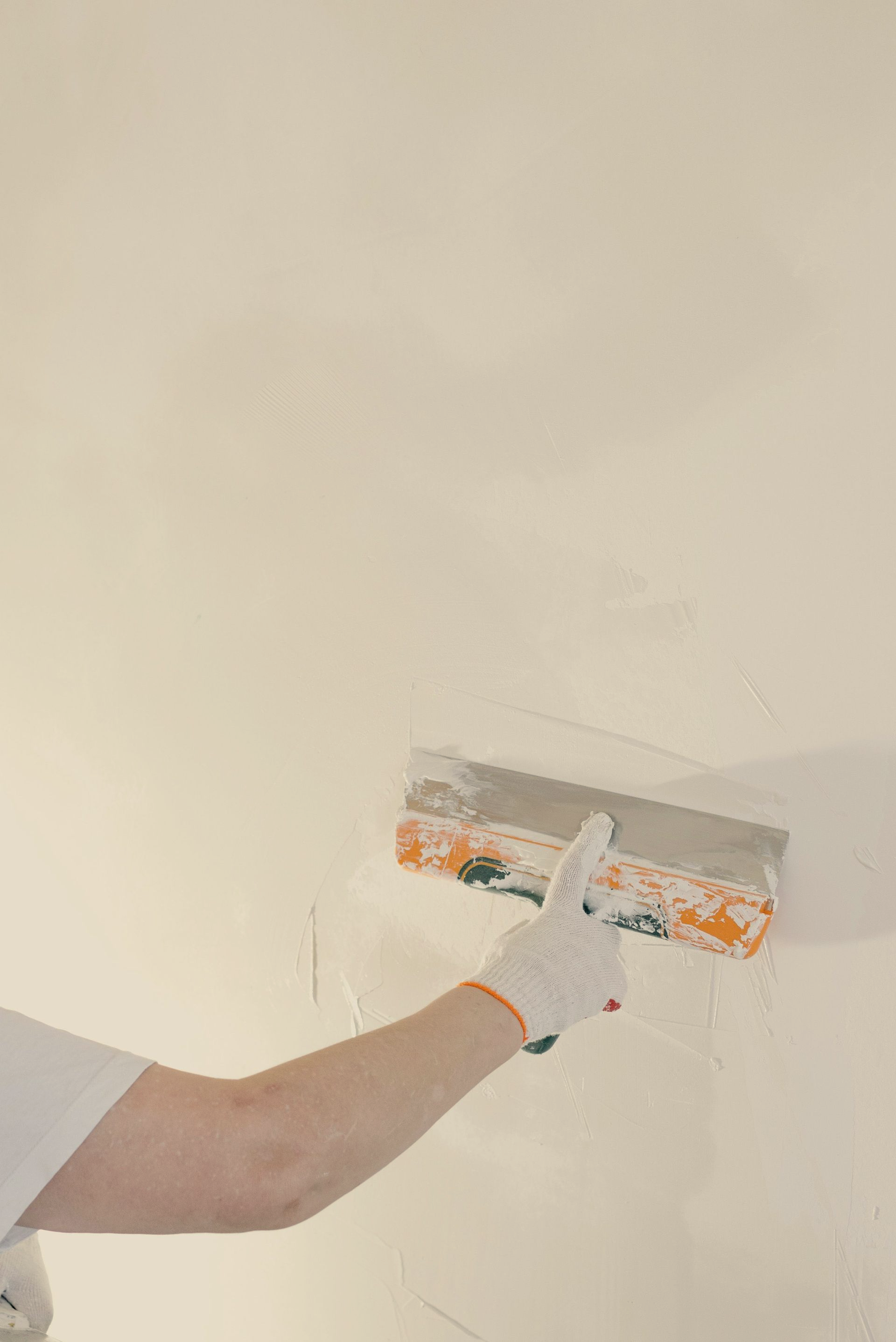 Personne utilisant une truelle pour lisser du plâtre blanc sur un mur.