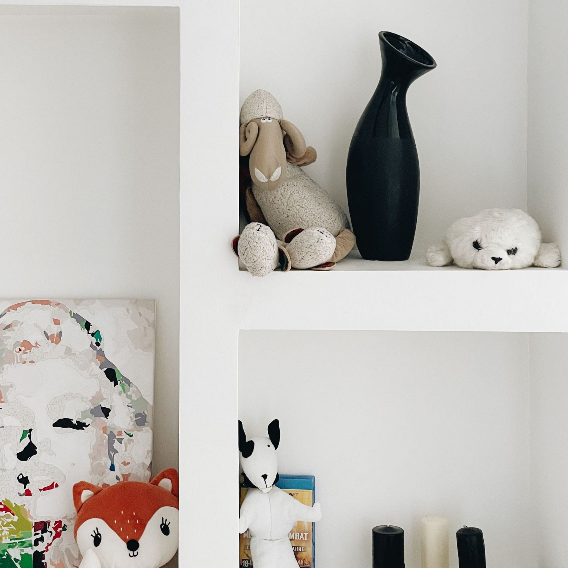 Étagères murales blanches avec des peluches et des vases dans une chambre d'enfant.
