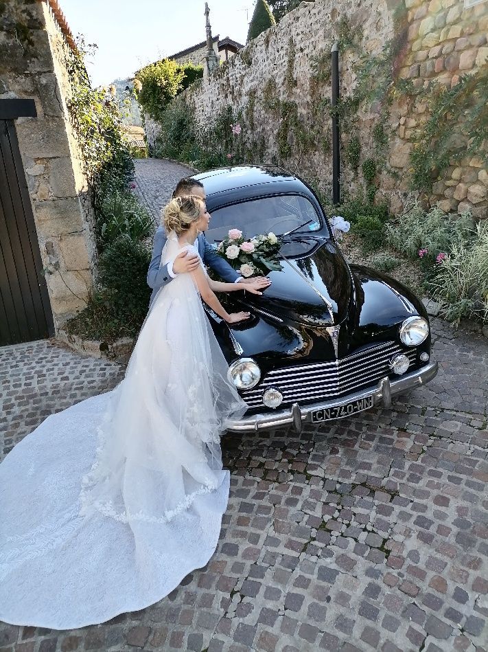 Des mariés avec les mains posées sur une voiture