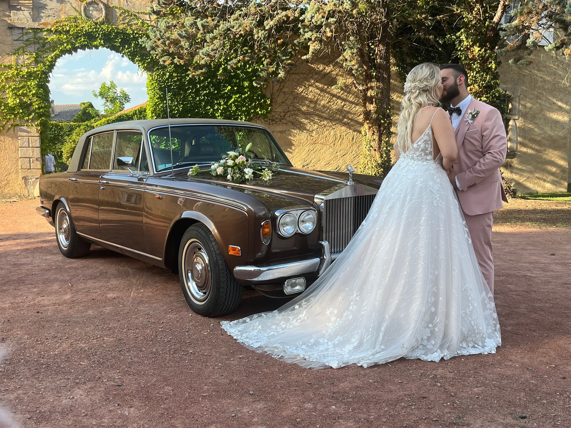 Des mariés et une voiture devant une arche