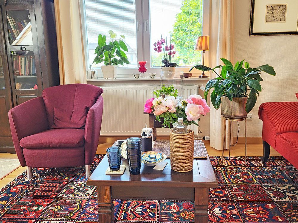 Ein Wohnzimmer mit einem lila Stuhl und einem Couchtisch mit Blumen darauf