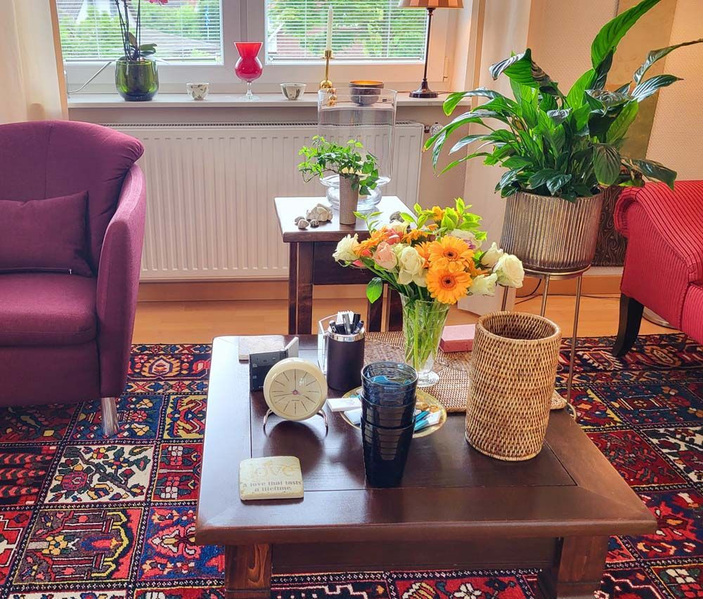 Ein Wohnzimmer mit einem lila Stuhl und einem Couchtisch mit Blumen darauf