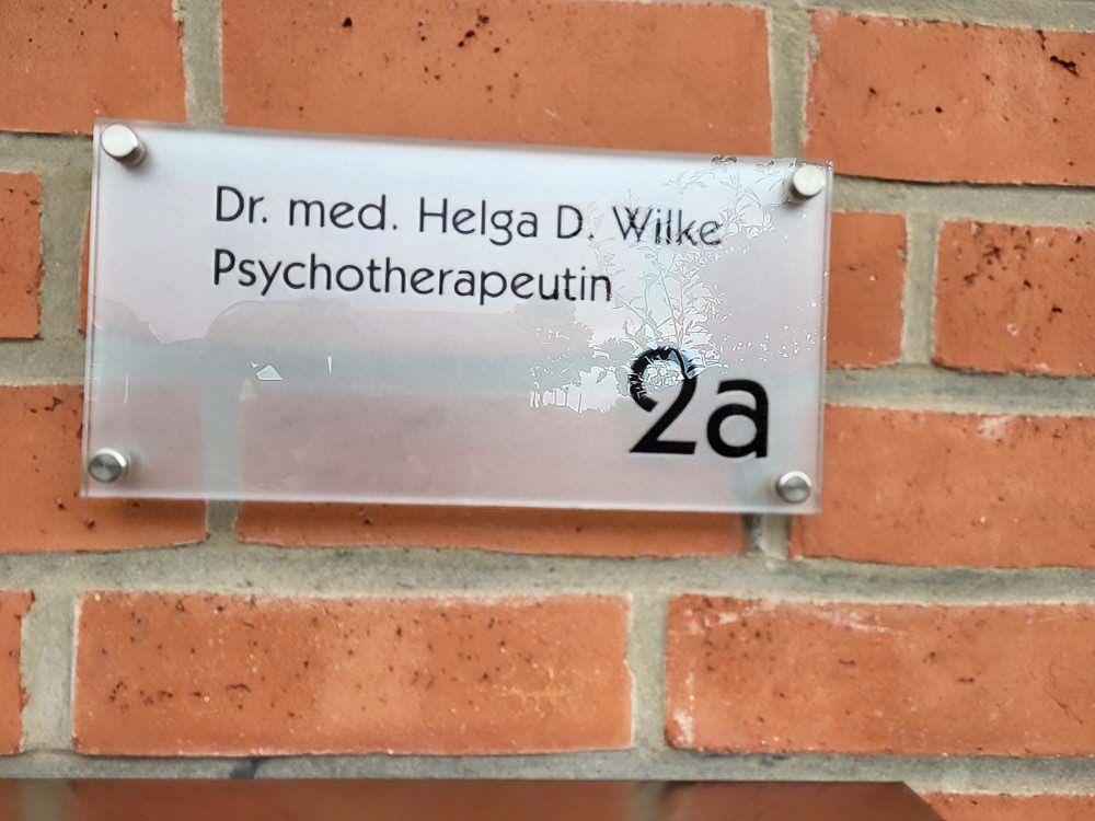 Ein Schild an einer Backsteinmauer sagt Dr. Med Helga D Wilke Psychotherapeutin