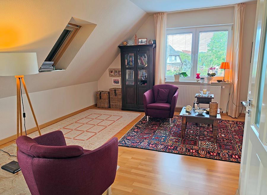 Ein Wohnzimmer mit einem lila Stuhl und einem Couchtisch mit Blumen darauf