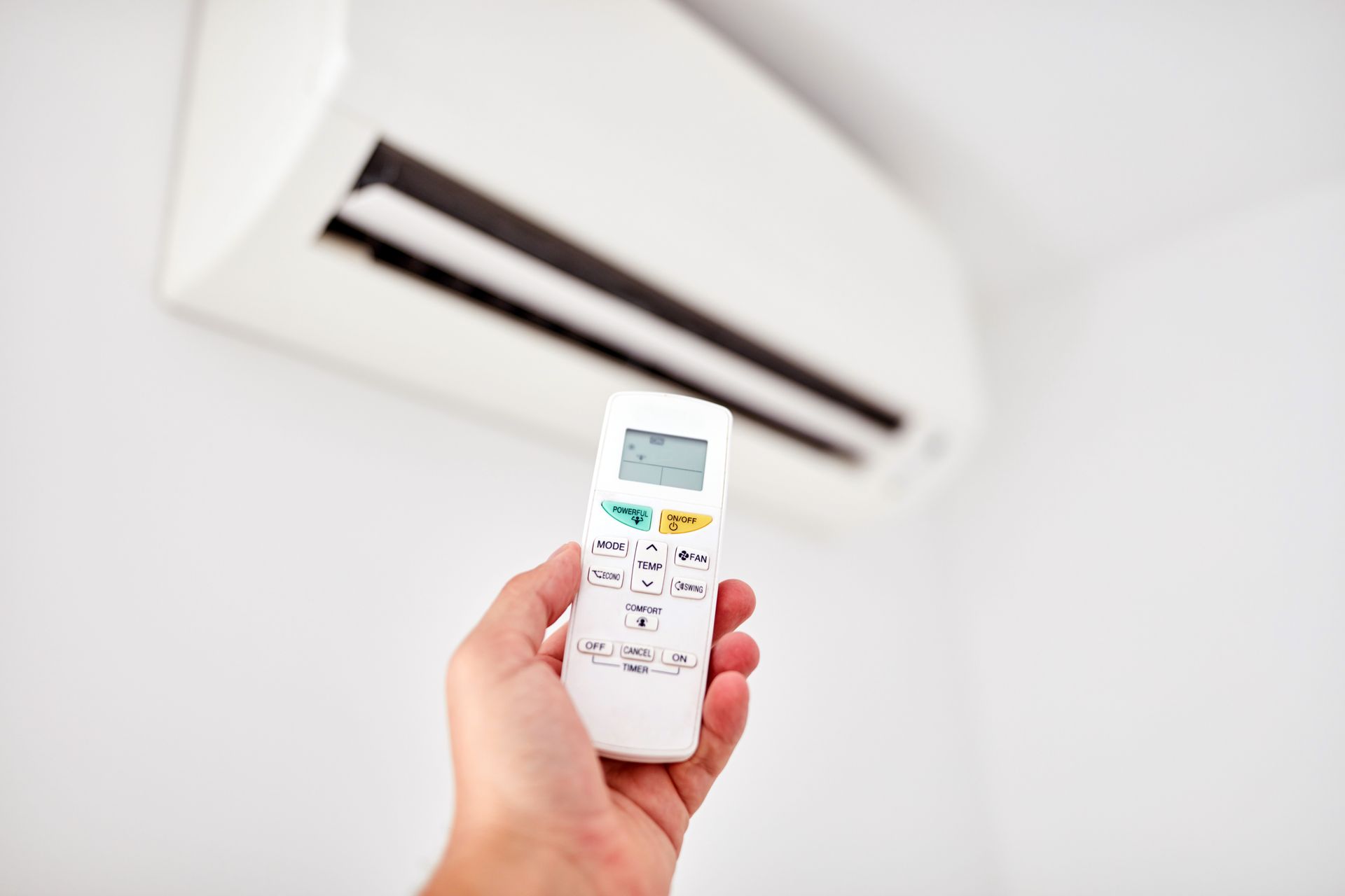 Bloc intérieur de climatisation avec main tenant une télécommande