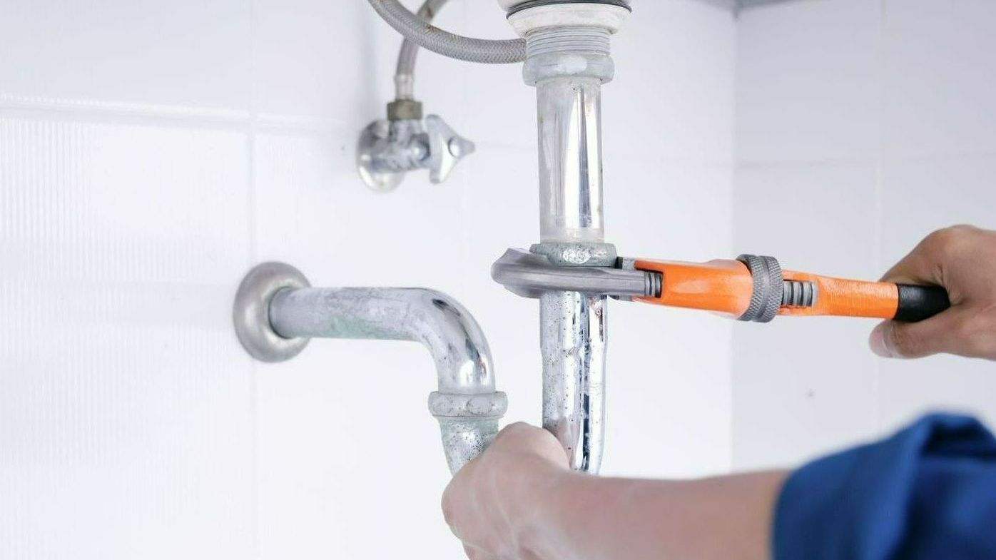 Plombier réparant une fuite d'eau sous un lavabo
