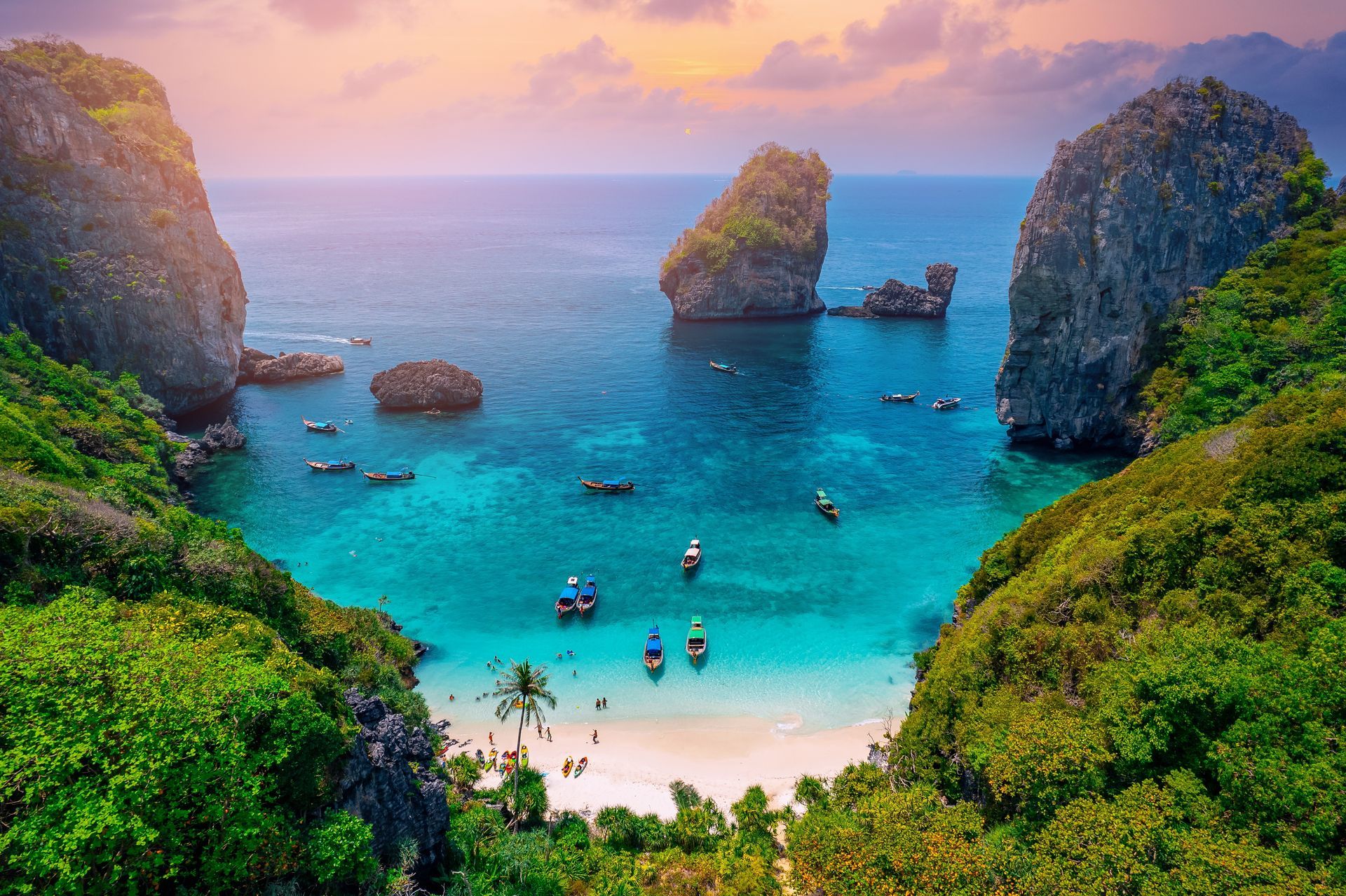An aerial view of a tropical beach with boats in the water.
