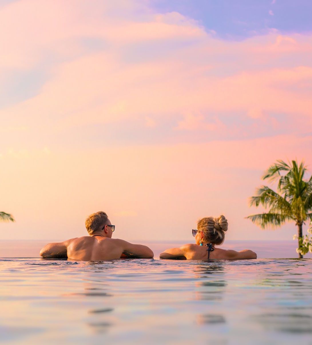A man and a woman are laying in an infinity pool.