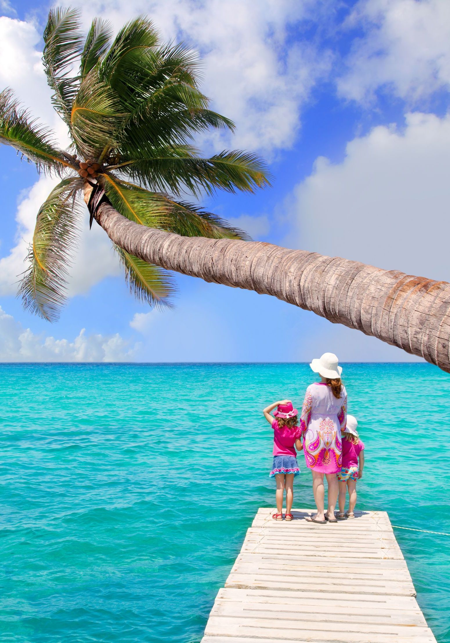 A woman and two children are standing on a dock overlooking the ocean.
