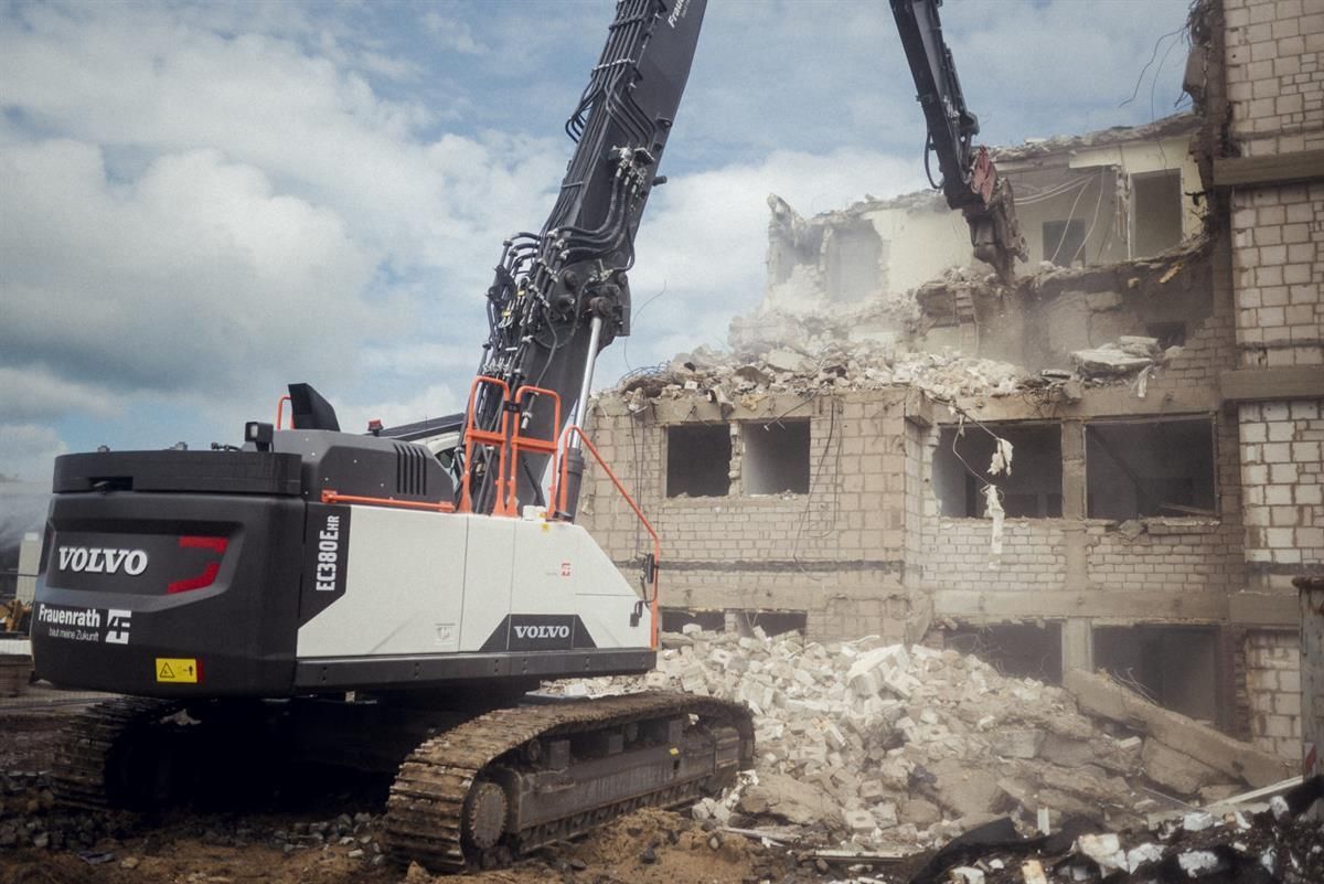 Ein großer Bagger zerstört ein großes Gebäude.