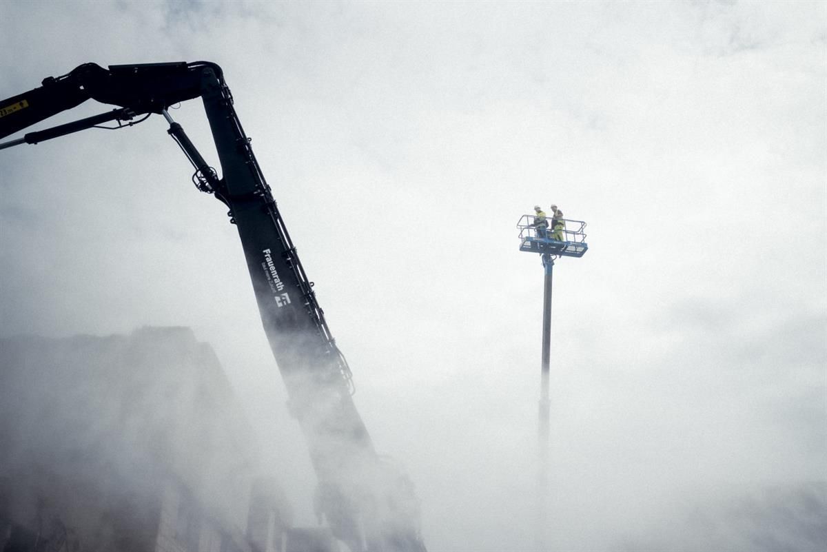 Ein Kran hebt einen Lichtmast im Nebel