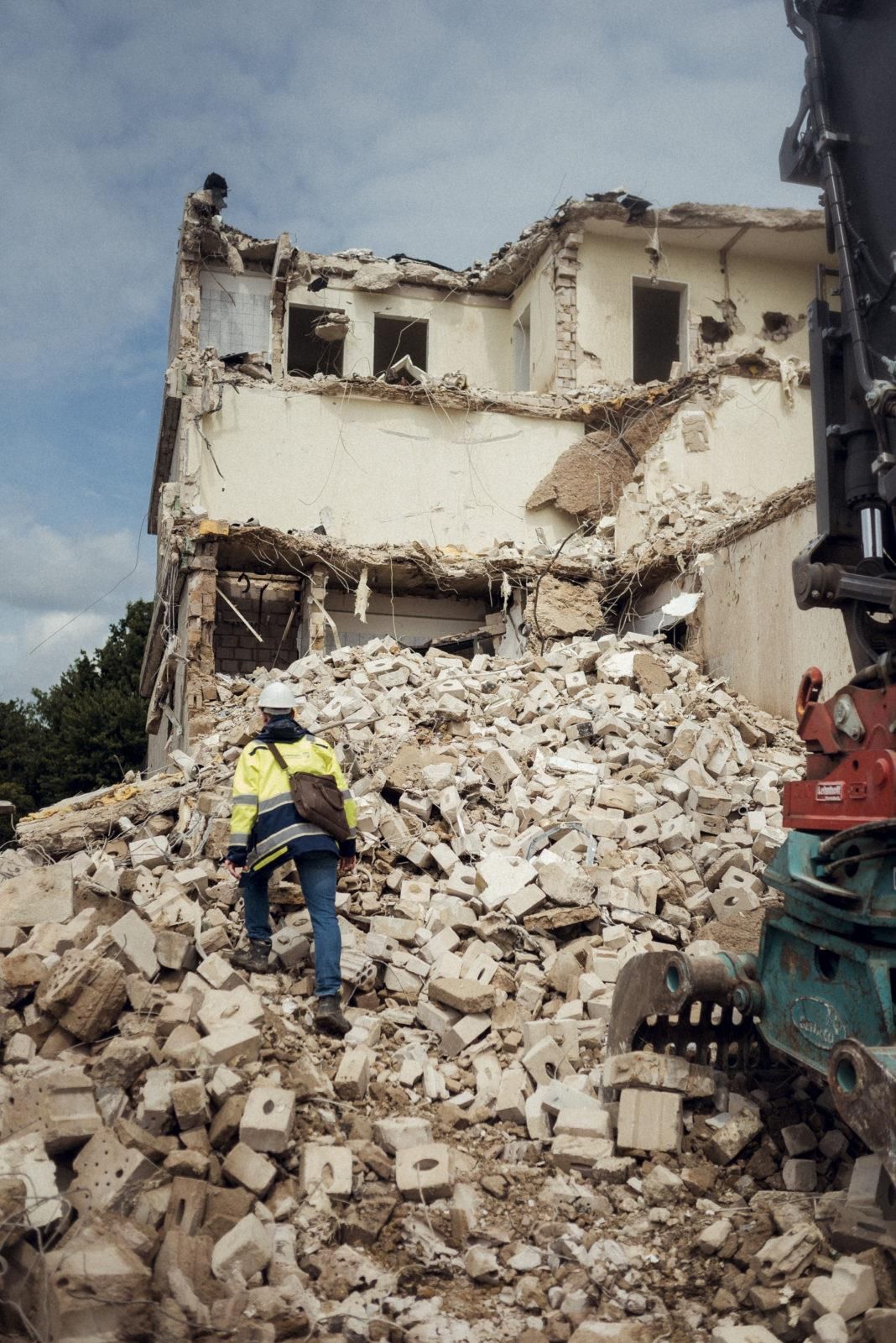 Ein Mann steht vor einem Trümmerhaufen.