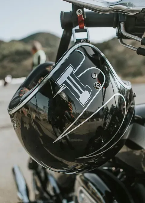 Un casco Harley Davidson negro cuelga del manillar de una motocicleta.