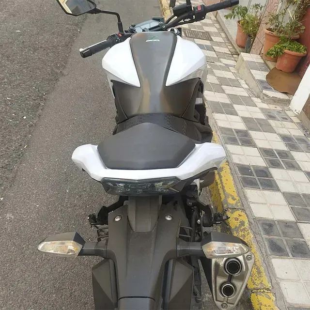 Una motocicleta blanca y negra está estacionada al costado de la carretera.