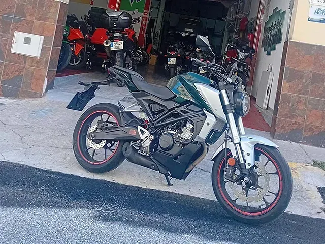 Una motocicleta verde y blanca está estacionada frente a un garaje.