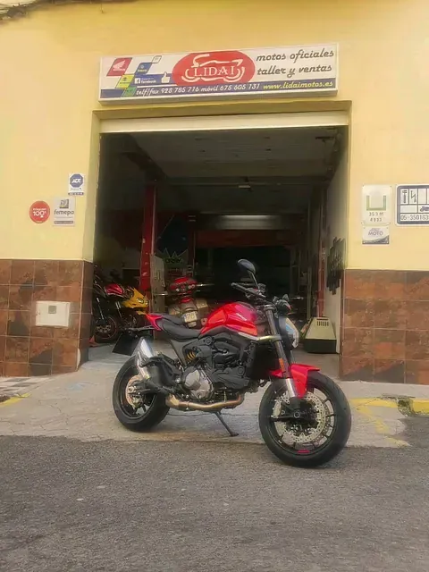 Una motocicleta roja está estacionada frente a un garaje.