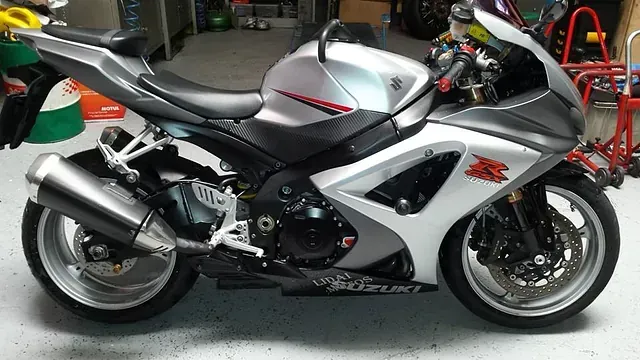 Una motocicleta Suzuki plateada y negra está estacionada en un garaje.