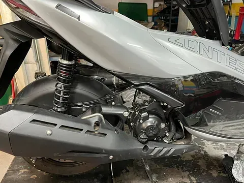 Un scooter está aparcado en un garaje con el tubo de escape visible.